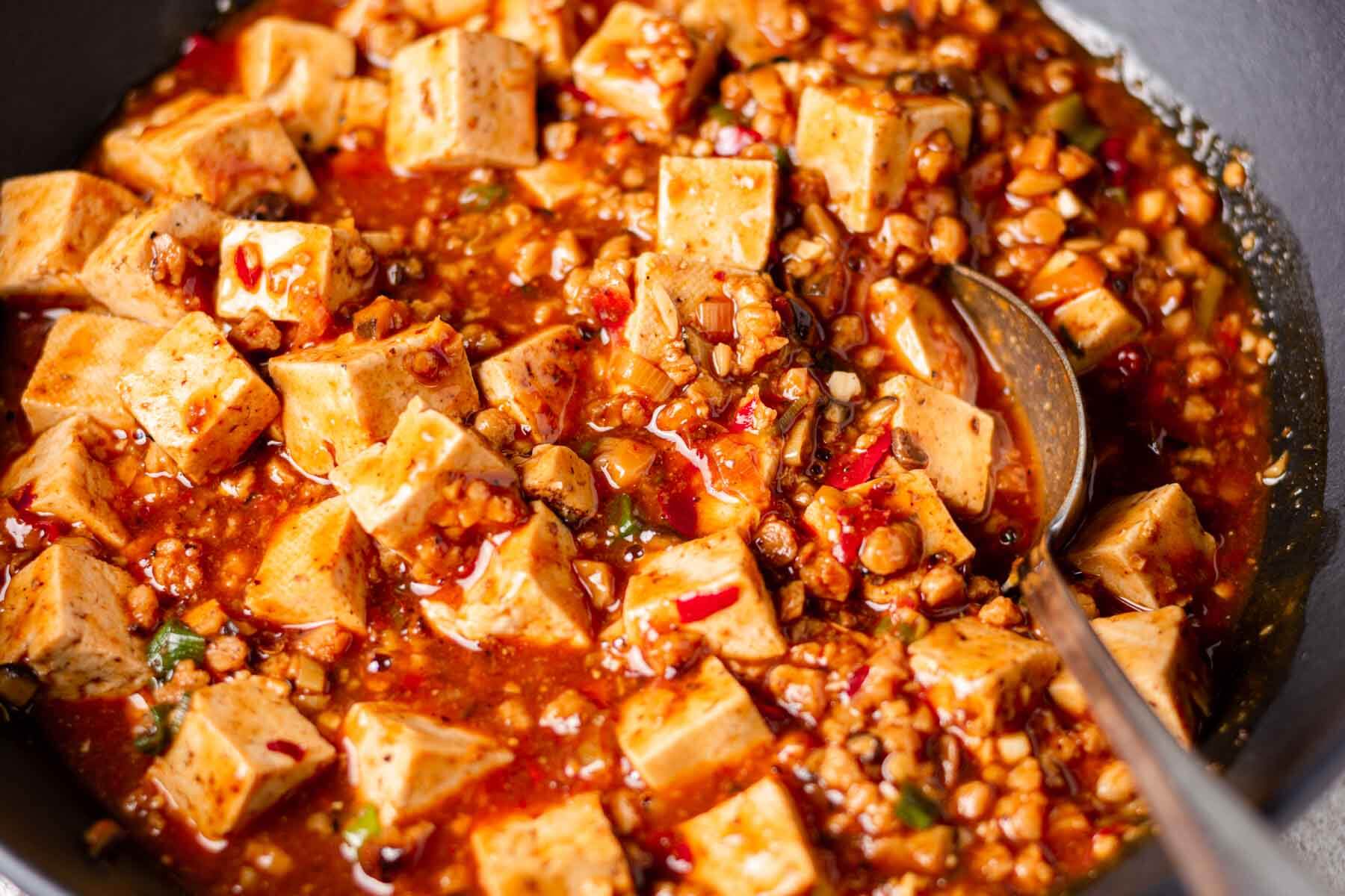 veganer mapo tofu mit löffel in schwarzem wok